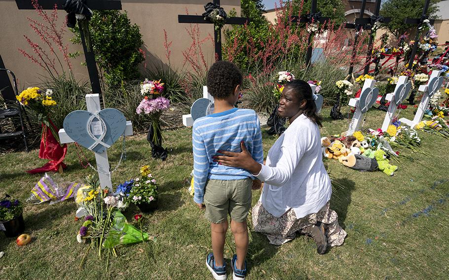 Dellandra Musa reassures her son Elijiah at a makeshift memorial in Allen, Texas