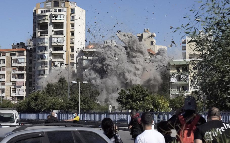 People watch a building collapse after being hit by an Israeli airstrike in Ghobeiri, Beirut, Lebanon, Tuesday, Oct. 22, 2024.