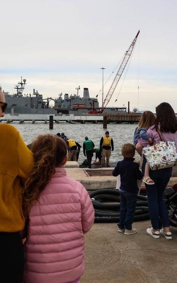 People look out into the water as they watch a submarine arrive