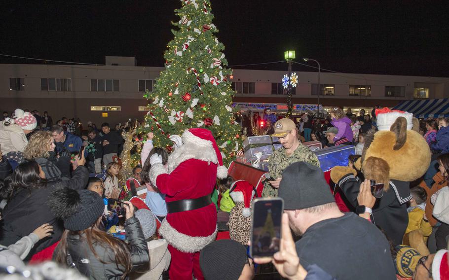 A crowd gathers around Santa and the Christmas tree.