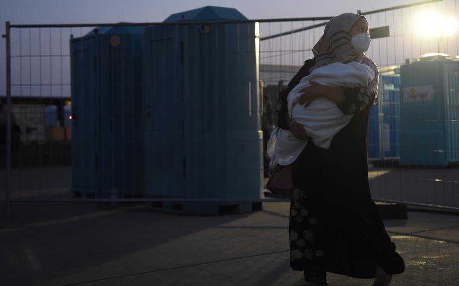 An Afghan woman clutches her baby before preparing to depart on a flight from Ramstein Air Base, Germany, to the United States, Sept. 2, 2021. So far more than 22,000 evacuees from Afghanistan have flown through Ramstein to the United States or other destinations.