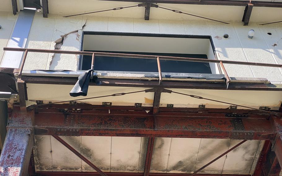 The damaged facade and exposed rusted metal of a building are seen from below.