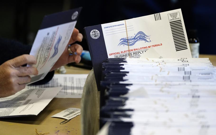 A stack of mail-in and absentee ballots are stacked on a table.