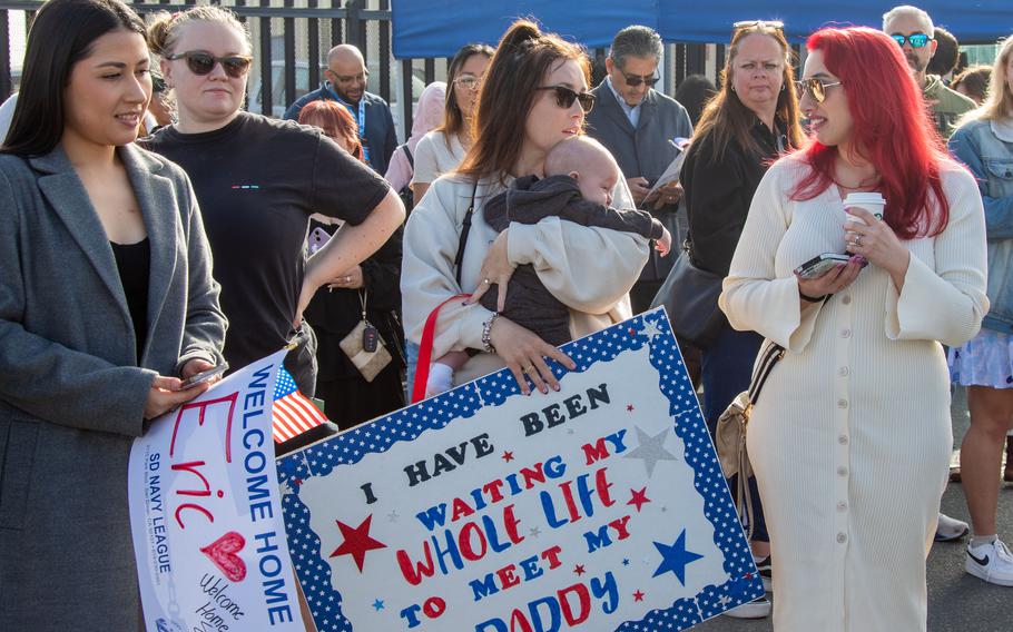 Family and loved ones hold signs during a homecoming ceremony for the USS Stockdale