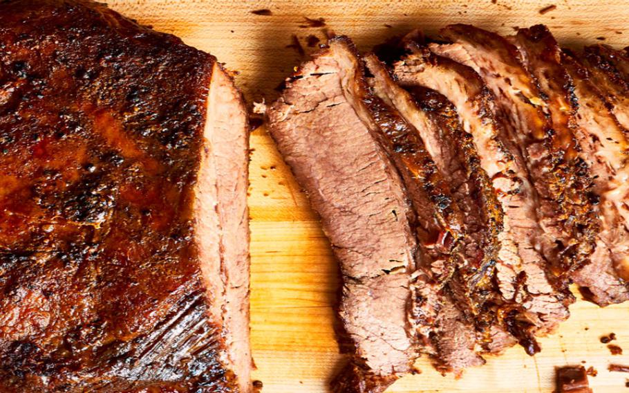 Meat is partially cut on a wooden cutting board.