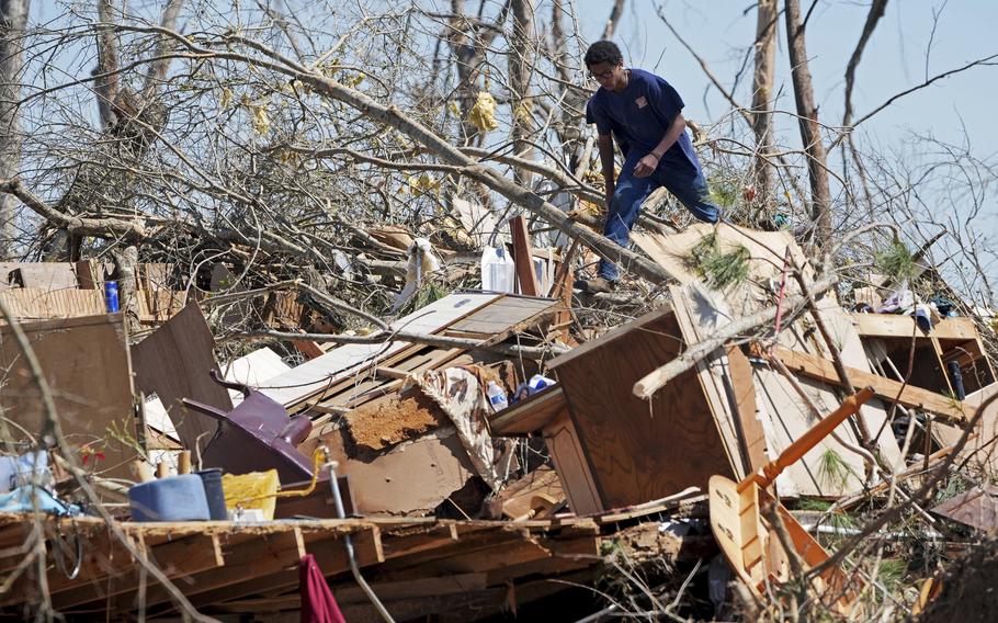 A man stands on top of the remnants of a home after a storm.