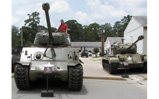 Museum Technician Stephanie VanderKnyff (Sapp) poses on a tank outside the U.S. Army Basic Combat Training Museum at Fort Jackson. The museum is celebrating its 50th anniversary.
