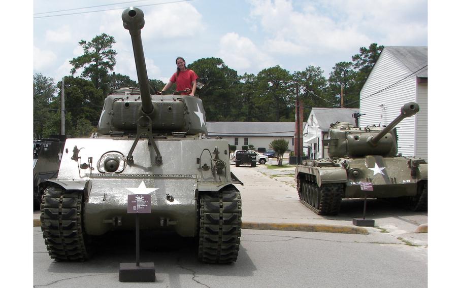 Museum Technician Stephanie VanderKnyff poses on a tank outside the U.S. Army Basic Combat Training Museum at Fort Jackson. The museum is celebrating its 50th anniversary. 