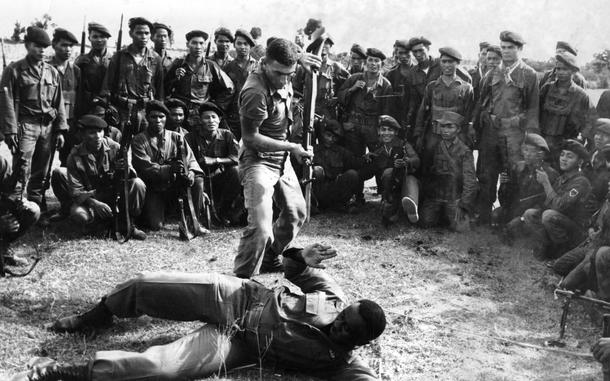 HED: Teaching tactics, 1962

Trung Lap Ranger Unit Training Center, South Vietnam, February, 1962:  U.S. Army advisers 1st Lt. Edmond Fricki (standing) and 1st Lt. Major Bell demonstrate hand-to-hand combat before a group of Republic of Vietnam Rangers. Republic of Vietnam troops receive training from instructors at the Trunglap Ranger Unit Training Center, some 30 miles north of Saigon. Some 11 Vietnamese instructors and 13 American advisers are providing special training in ranger fighting techniques to all men in the Army of the Republic of Vietnam (ARVN).

The article accompanying this photo noted that the "graduates bring into the rough-and-tumble fight with Viet Cong communist guerrillas the necessary tough, flexible tactics needed to fight in rough terrain with unorthodox methods."

Looking for Stars and Stripes’ coverage of the Vietnam War? Subscribe to Stars and Stripes’ historic newspaper archive! We have digitized our 1948-1999 European and Pacific editions, as well as several of our WWII editions and made them available online through https://starsandstripes.newspaperarchive.com/

META TAGS: Pacific; South Vietnam; Vietnam War; Vietnamese army rangers; training; Army of the Republic of Vietnam (ARVN); Military Assistance Advisory Group (MAAG); Trunglap; Trung Lap