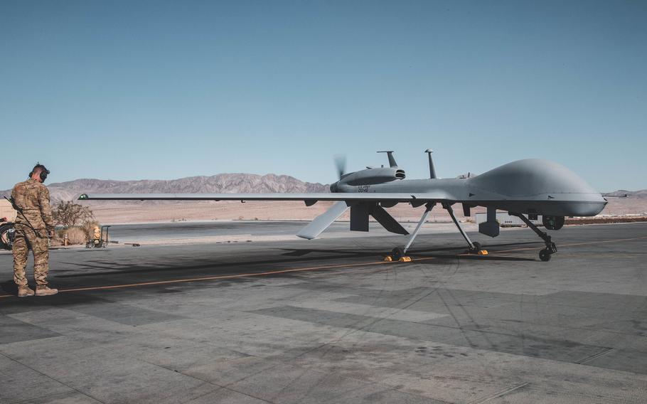 A service member stands near a MQ-1C drone on the flightline at Twentynine Palms.