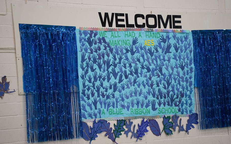 A blue poster filled with painted handprints from students.