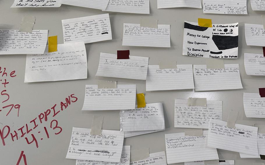 Index cards describing why the recruits joined the Army are taped to a large board.