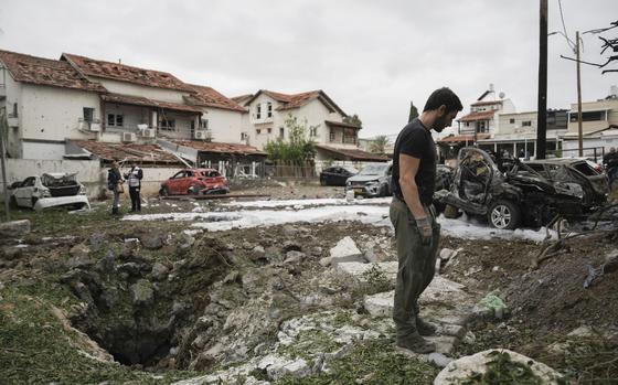 A member of the Israeli police bomb squad examines the damage from Hezbollah rockets outside Tel Aviv.