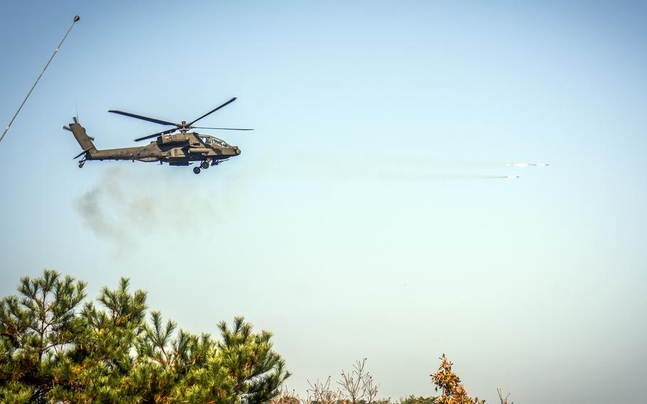 An Apache helicpter, seen from below, fires a rocket.