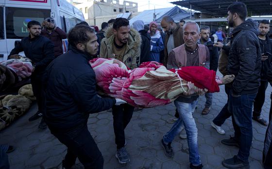 Palestinians carry the body of a relative killed in the Israeli bombardment of the Gaza Strip at a hospital in Deir al-Balah, Sunday, Dec. 15, 2024. (AP Photo/Abdel Kareem Hana)