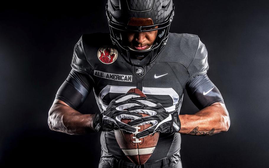 An Army player holds a football and looks down.