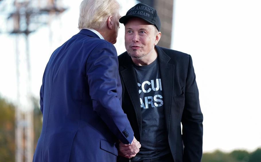 Elon Musk shakes hands with Donald Trump.