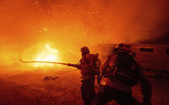 Firefighters spray water on a fire.