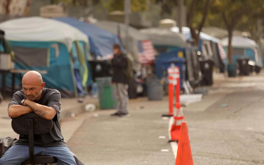 A homeless veteran sits outside his tent along Veterans Row on a Saturday morning along San Vicente Boulevard in an unincorporated area near Brentwood on October 30, 2021. Clearing of the encampments will begin at 7 a.m. on Monday, November 1 and the homeless vets will be moved to individual tents on the VA campus. Veterans Affairs Secretary Denis McDonough, who visited the encampment in October, said last week that the about 40 veterans from Veterans Row would be housed by November. 