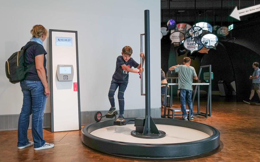 A boy tests his balance on a circular cycling station at the Experimenta Science Center, discovering the principles of physics and motion.