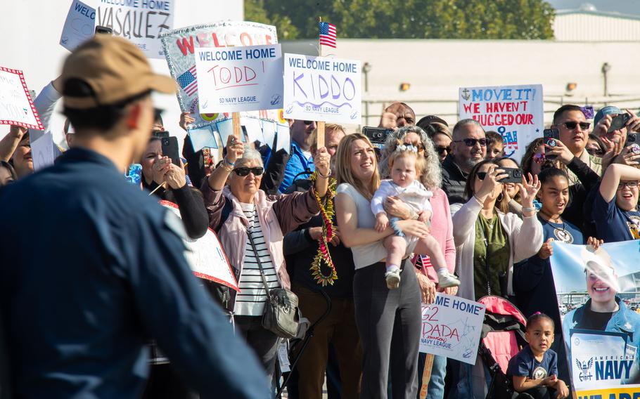 Family and loved ones hold signs during a homecoming ceremony for the USS Stockdale