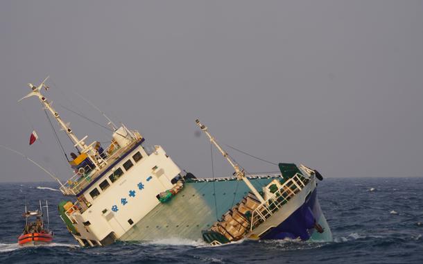 The cargo ship Shayesteh lists as a U.S. Coast guard rescue team arrives by rigid hull inflatable boat.