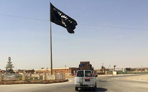 FILE - A motorist passes by a flag of the Islamic State group in central Rawah, 175 miles (281 kilometers) northwest of Baghdad, Iraq, on July 22, 2014. The U.S. Central Command said Wednesday, July 17, 2024 that the Islamic State group is trying "to reconstitute” as the number of attacks in Syria and Iraq is on track to double those of the previous year. (AP Photo, File)
