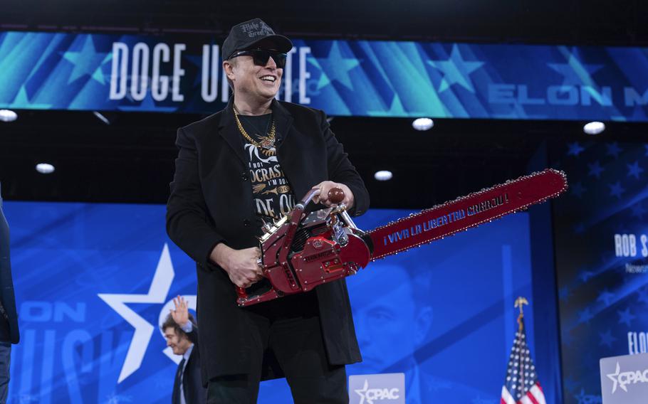 Musk holds a chainsaw.