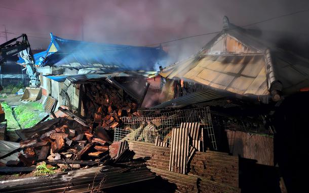 Wisps of smoke rise from the smoldering remains of a destroyed house that burned down.