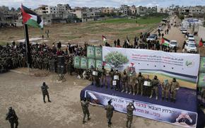 An aerial view of hostages on a stage surrounded by Hamas fighters.