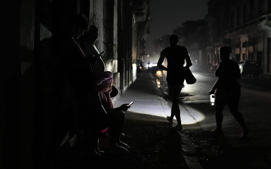 Residents walk on a street during a general blackout in Havana