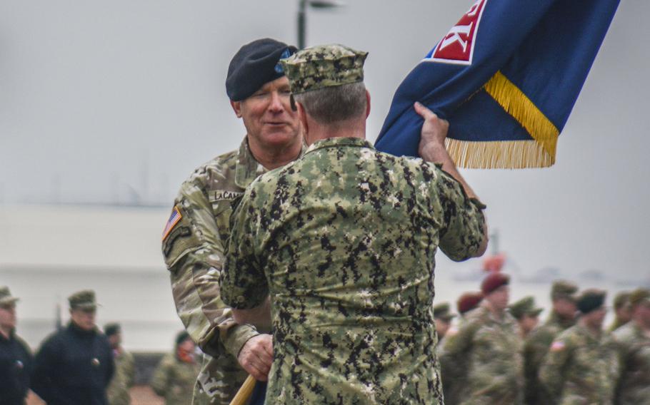 U.S. Army Gen. Paul LaCamera, at left, passes a military flag to Adm. Samuel Paparo.