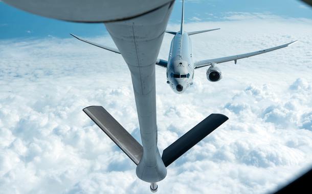 P-8A Poseidon flies above clouds and approaches a KC-135 Stratotanker to refuel.