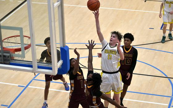 Alconbury center Aaron Dudley floats a shot over Baumholder defenders Leo Kirkland, center left, and Gregory Makubuya, bottom center, during a Division III pool-play game at the 2025 DODEA European basketball championships on Feb. 13, 2025, at the Wiesbaden Sports and Fitness Center on Clay Kaserne in Wiesbaden, Germany.