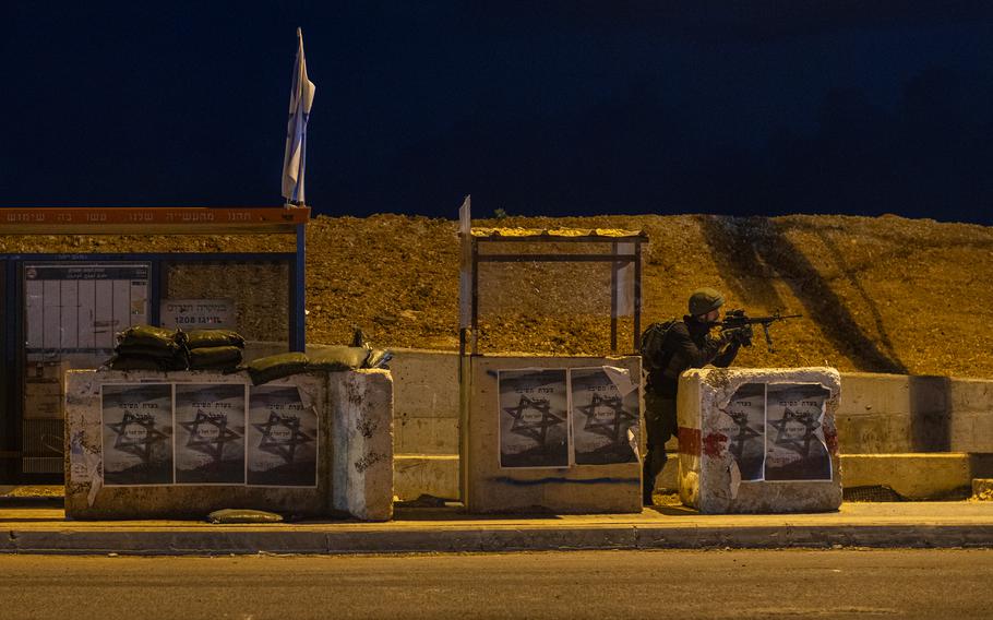 An Israeli soldier stands guard at a bus stop near Tapuach Junction in the West Bank.