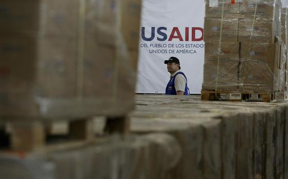 FILE - A man walks past boxes of USAID humanitarian aid at a warehouse at the Tienditas International Bridge on the outskirts of Cucuta, Colombia, Feb. 21, 2019, on the border with Venezuela. (AP Photo/Fernando Vergara, File)