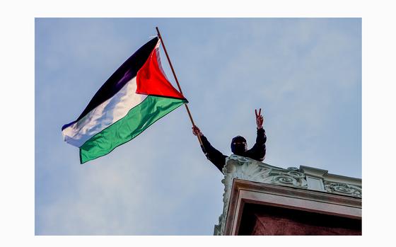 A student protester waves a Palestinian flag above Hamilton Hall on the campus of Columbia University, on Tuesday, April 30, 2024, in New York. Early Tuesday, dozens of protesters took over Hamilton Hall, locking arms and carrying furniture and metal barricades to the building. Columbia responded by restricting access to campus. 