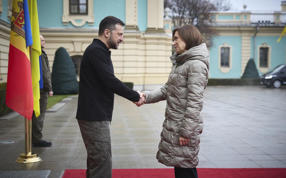 Ukrainian President Volodymyr Zelenskyy shakes hands with the president of Moldova; the side profiles of both are seen from the knees up.