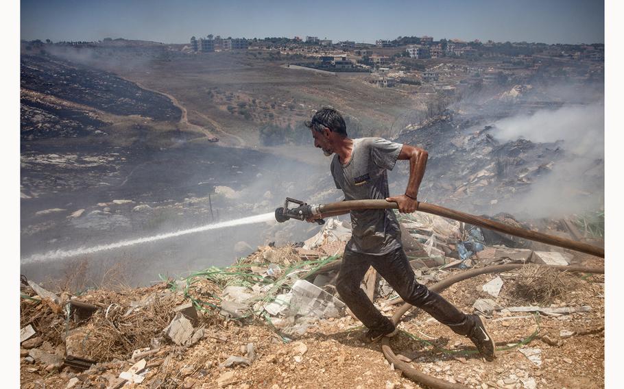Civilians try to put out fires caused by multiple Israeli strikes that hit targets next to the town’s main road on June 26, 2024, in Bint Jbeil, Lebanon. 