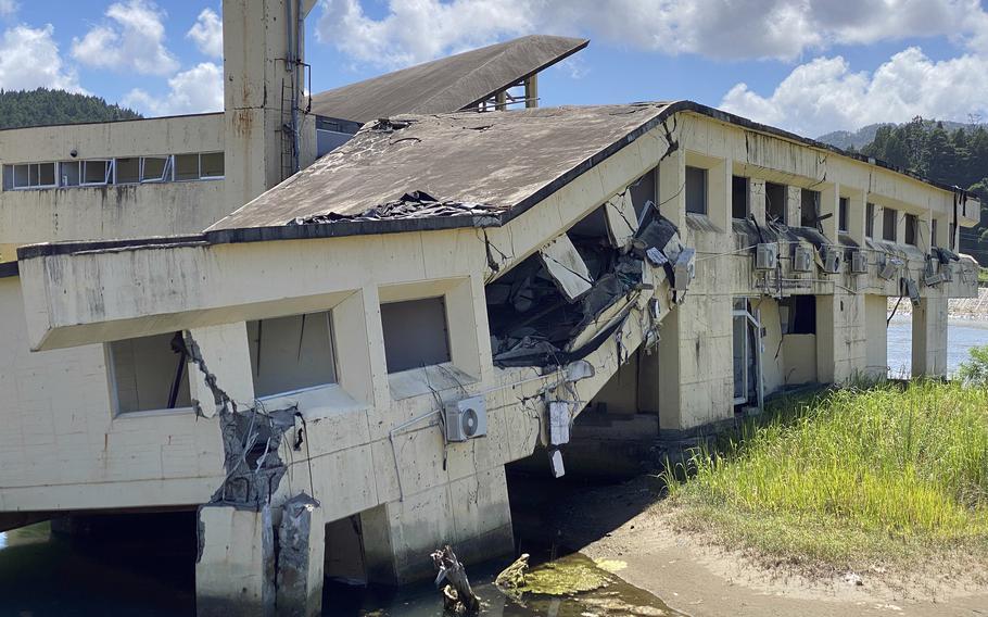 A damaged white building stands against a backdrop of blue sky and white clouds.