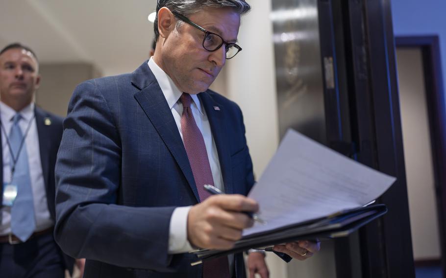 Mike Johnson holds and examines a folder with paper resting on it.