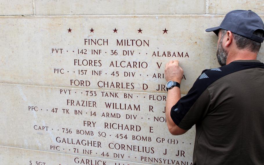 An American Battle Monuments Commission staff member places a bronze rosette next to the name of U.S. Army Pfc. Alcario V. Flores on the Wall of the Missing on July 23, 2024, at the Epinal American Cemetery in Dinozé, France. The rosette signifies that Flores has been accounted for.