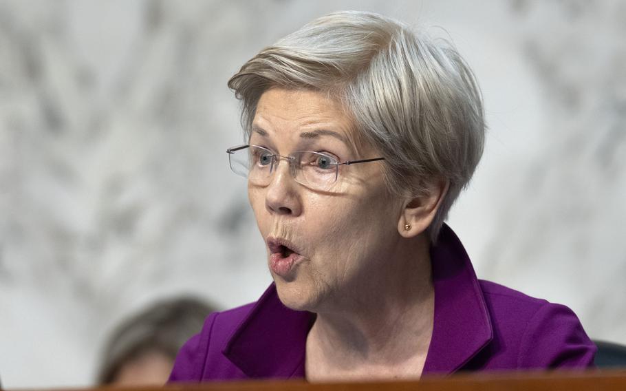 Warren seated and asking a question at a hearing.