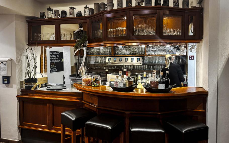 The inviting bar at Hirschens Restaurant Wirtsstuben in Parsberg, Germany, offers a quaint spot to enjoy a drink, surrounded by warm lighting and rustic charm.