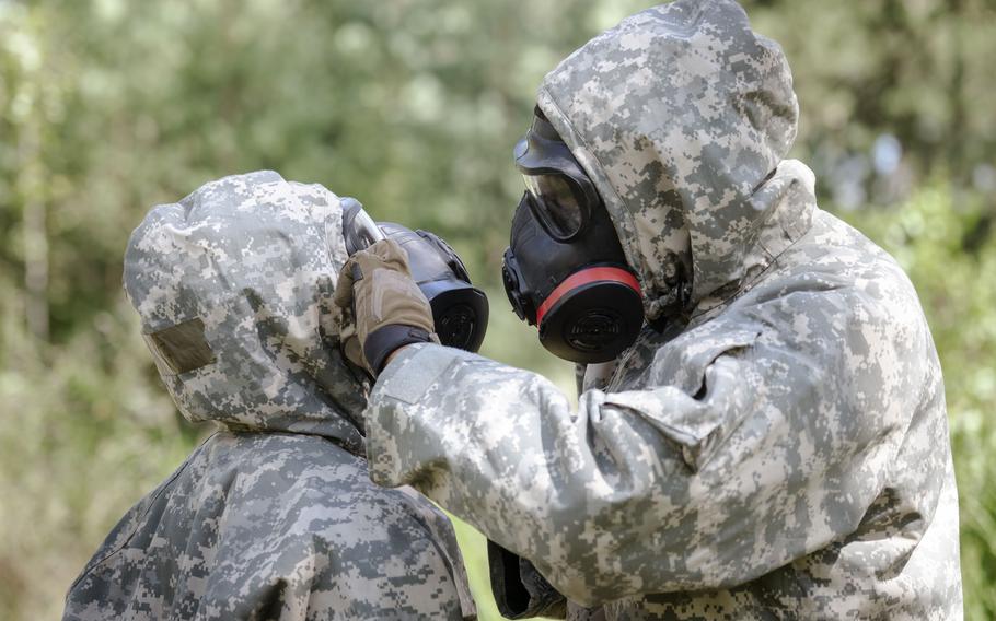 Soldiers with 10th Army Air and Missile Defense Command help each other prepare for a simulated gas attack during U.S. Army Europe and Africa’s Best Squad Competition at Grafenwoehr Training Area in Germany.