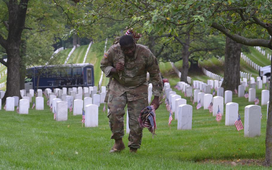 Kahvontey Woodburry places flags at the graves of those buried at Arlington National Cemetery for “Flags In” on Thursday, May 23, 2024, to honor fallen service members for Memorial Day. This group of soldiers started in sections 41, 42 and 43 of the cemetery.   