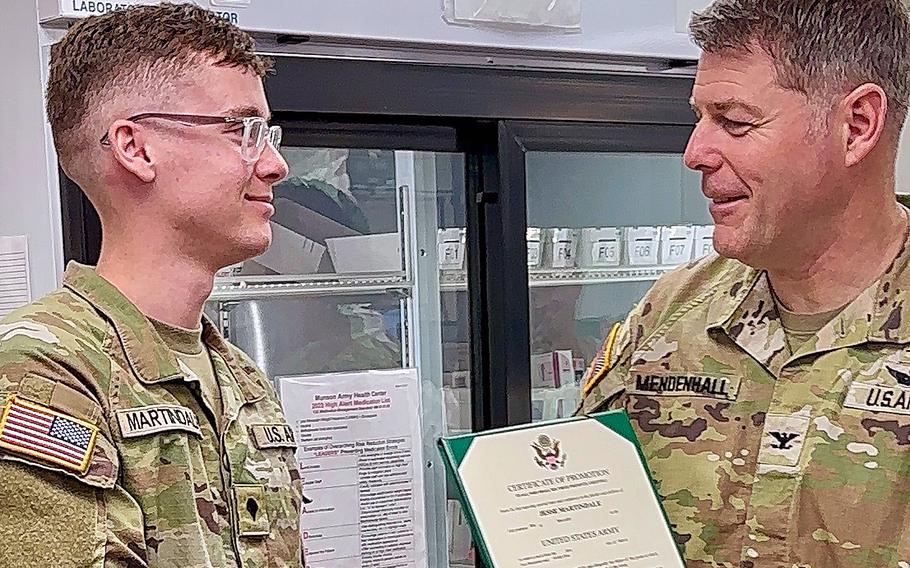 A colonel shakes hands with a soldier and gives him a certificate.