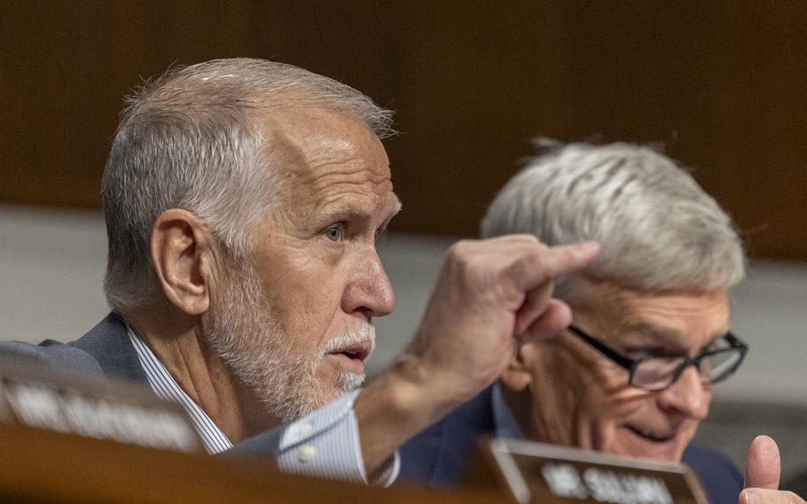 Tillis seated at a hearing with his hand raised and his pinky extended.