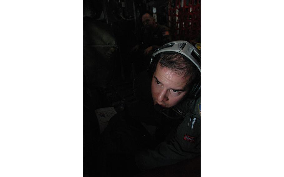 Staff Sgt. Nick Alarcon, a C-130 loadmaster from the 36th Airlift Squadron from Yokota Air Base, looks out the window of a cargo plane 