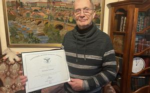 A retired U.S. Army major holds a certificate signed by President Joe Biden.